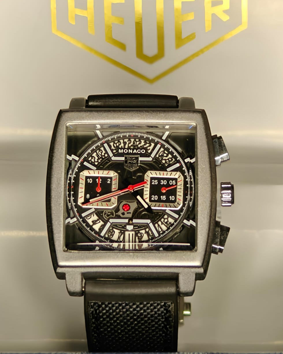 Watch with a detailed face on a metallic background featuring the Heuer logo.